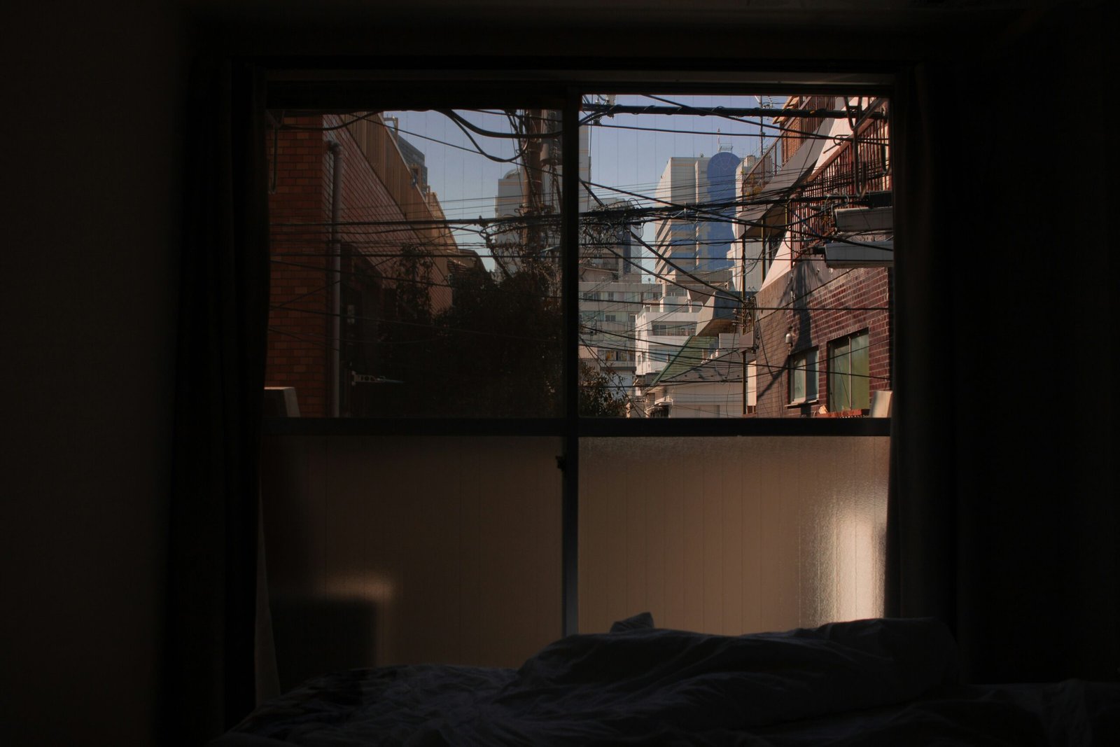 Bright city light streaming into a bedroom window, showing why blackout curtains matter for sleep