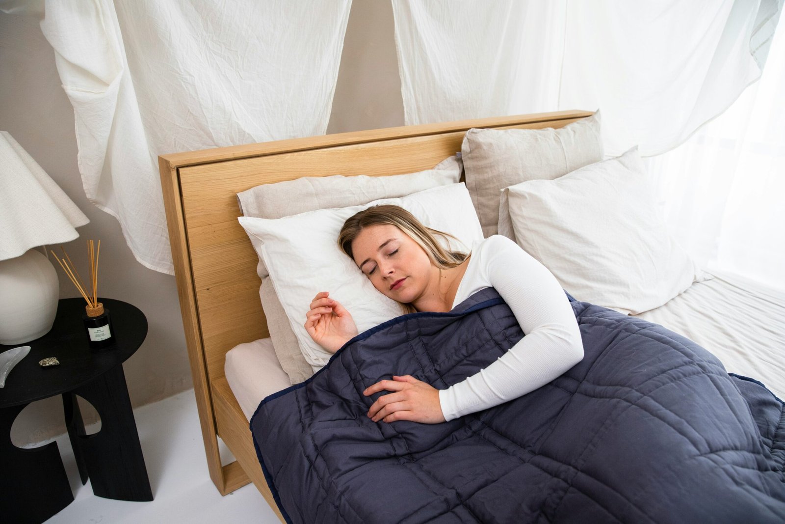 Person under a soft blue weighted blanket in a calm bedroom