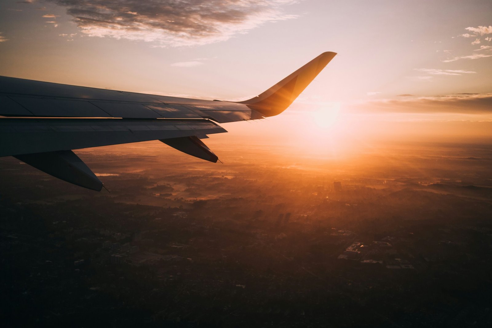 Sunrise view from airplane window over city, representing resetting circadian rhythm after travel