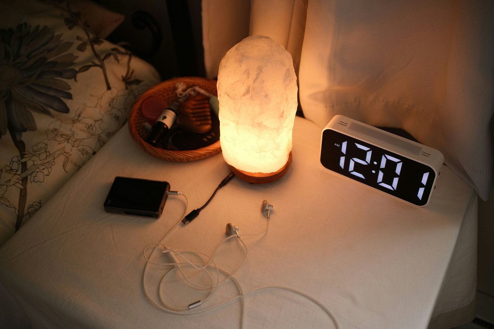 Bedside nightstand with alarm clock and soft lamp, symbolizing sleep timing and consistent bedtime