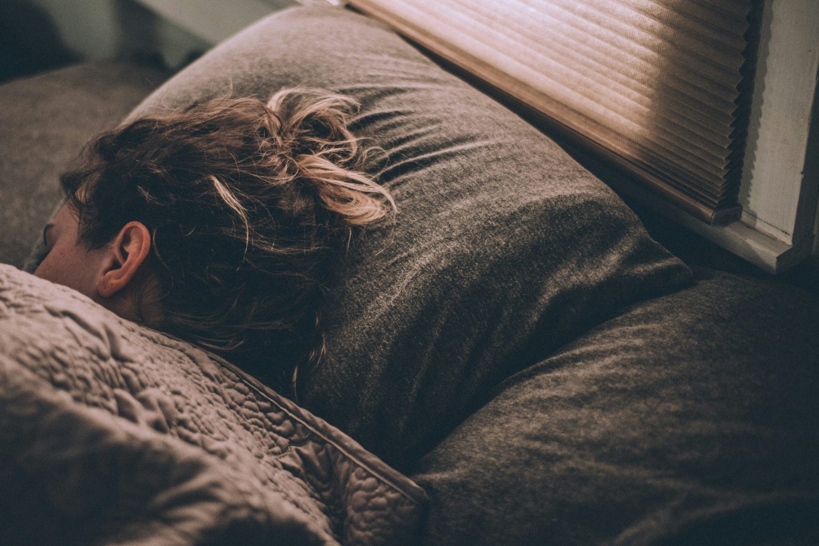 Person sleeping peacefully in bed under soft natural light, representing healthy sleep duration
